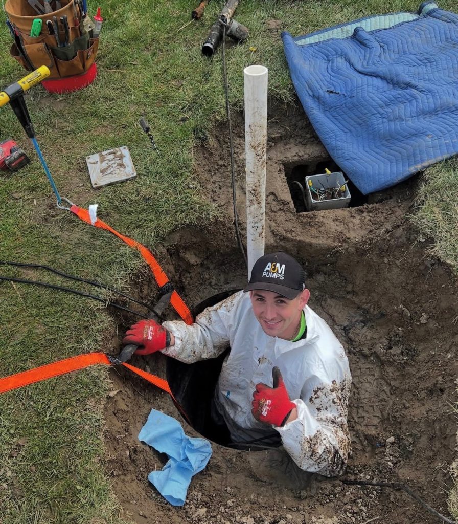 A&M Pumps technician lowering a replacement effluent pump into a septic tank in Northern Westchester, NY
